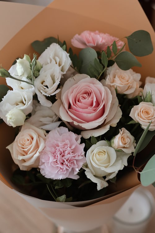 Wrapped bouquet of blush pink and white roses with eucalyptus