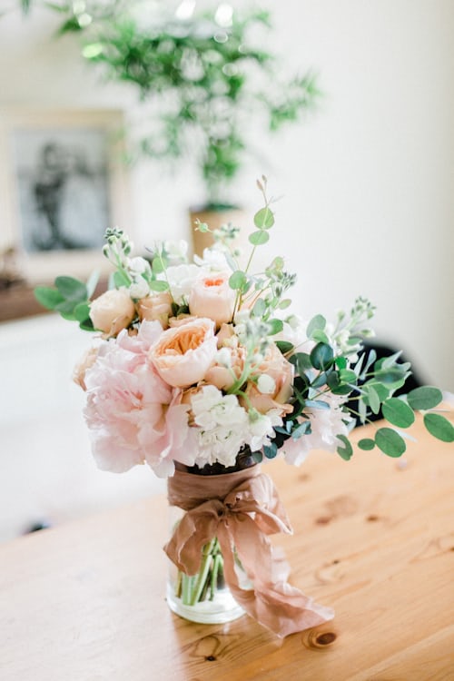 Peach and blush peony and rose bouquet in a vase with silk ribbon